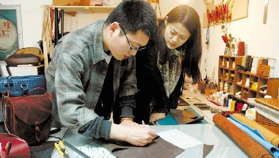 图为王青臣和夏亚桂在制作皮具.